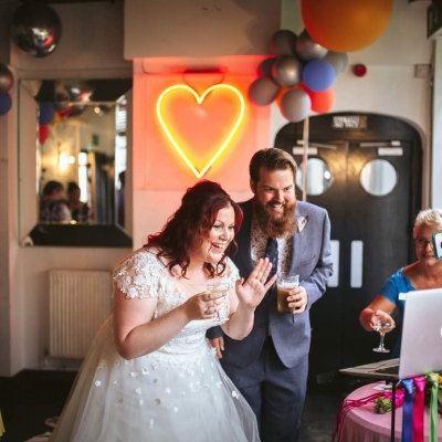 Bride and groom wave at their virtual guests on Zoom
