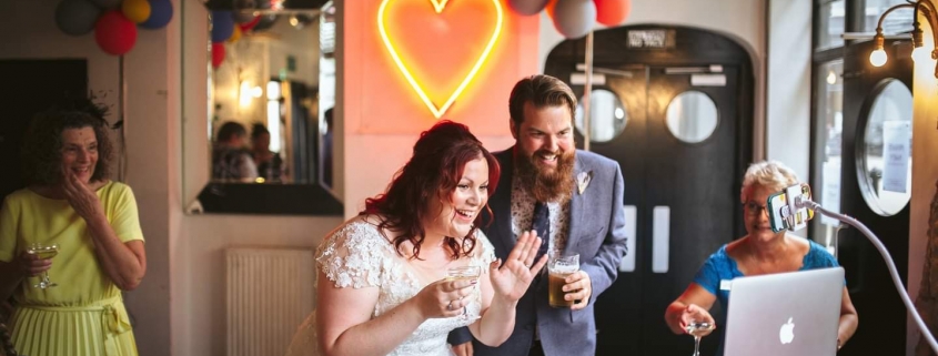 Bride and groom wave at their virtual guests on Zoom