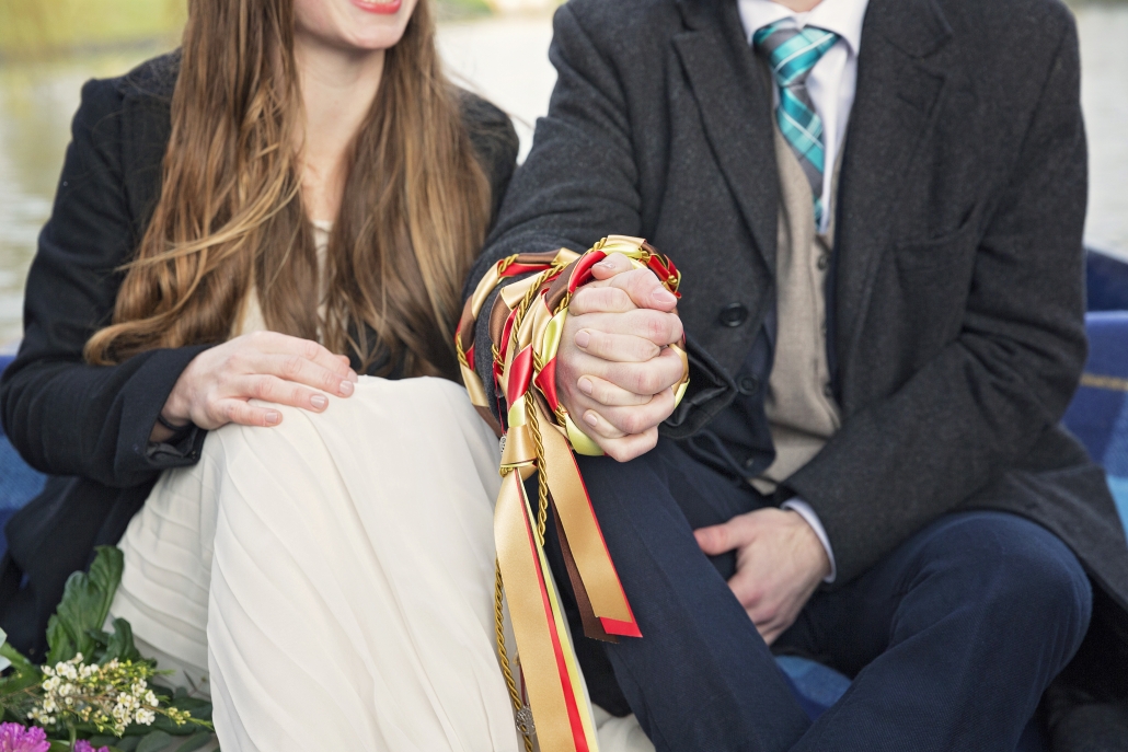 Two hands joined by gold and red ribbons